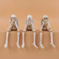 Lot de trois squelettes décoratifs assis à jambes pendantes